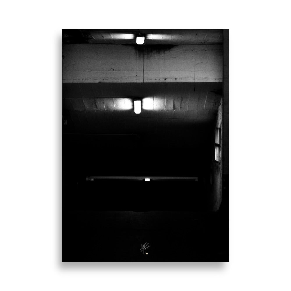 Photographie en noir et blanc intitulée 'Glaçant', montrant trois néons blancs éclairant une entrée de garage descendante dans une atmosphère sombre et mystérieuse.