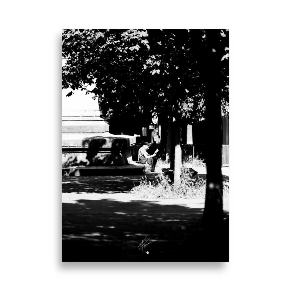 Poster photographique 'L'heure de lire', capturant un homme lisant un livre à Paris, en noir et blanc.