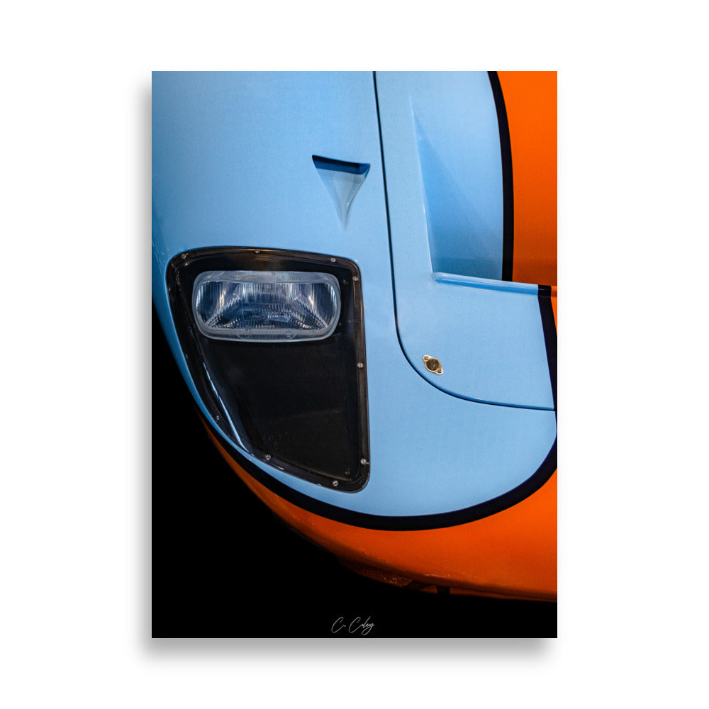 Poster 'GT40 Gulf' capturant la nostalgie de la Ford GT40 à travers un détail du bloc optique vintage et du capot bleu et orange, offrant une plongée visuelle dans l'histoire légendaire des courses automobiles par le photographe Charles Coley.