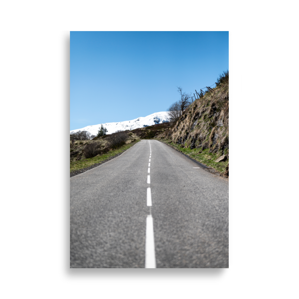 Photographie de route rurale menant à une montagne enneigée sous un ciel bleu dans le Cantal - Poster de paysage du Cantal