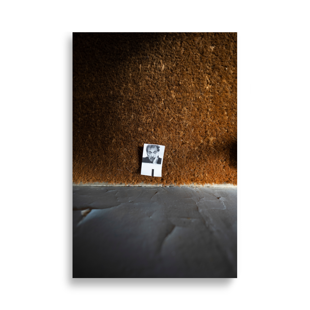 Poster d'une photographie représentant une petite photo posée sur un tapis à l'entrée d'un immeuble parisien.