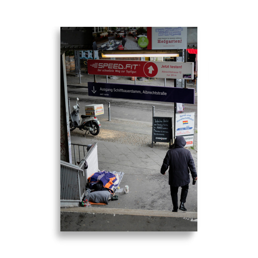 Photographie 'Contrastes de Berlin' montrant un homme sans domicile fixe reposant sous le métro berlinois, juxtaposé à un scooter de livraison alimentaire