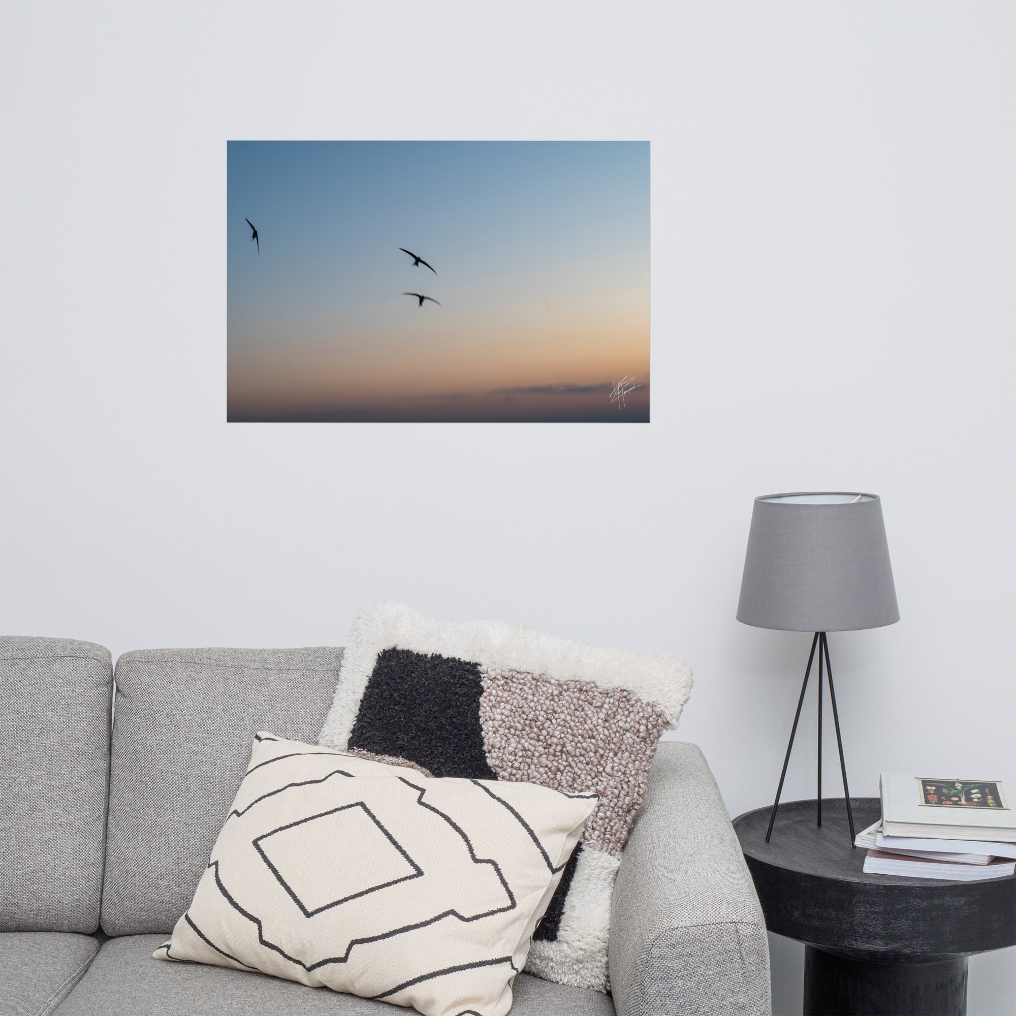 Trois oiseaux volant dans un ciel aux teintes de bleu, orange et jaune.