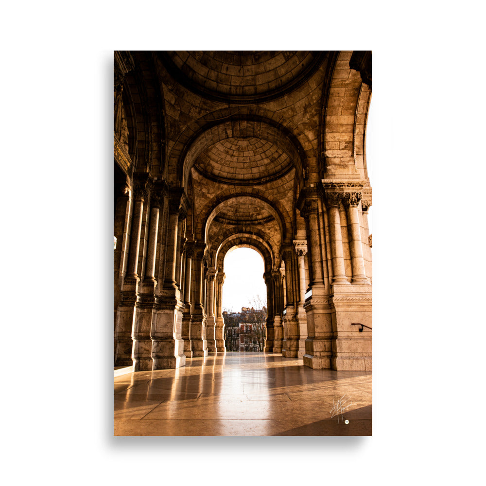 Photographie ensoleillée de la façade de l'entrée de la Basilique du Sacré Cœur à Montmartre, montrant l'architecture détaillée avec des reflets lumineux sur le sol pavé.