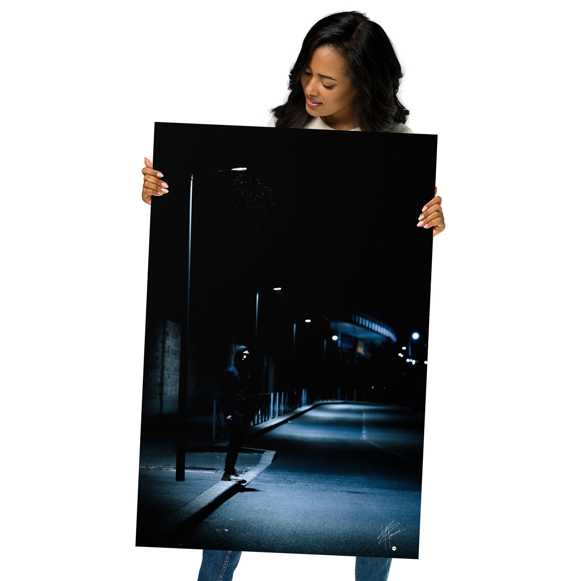 Photographie nocturne d'un homme à capuche se tenant sous un lampadaire près d'une station de métro à Créteil, émanant une atmosphère sombre et énigmatique.