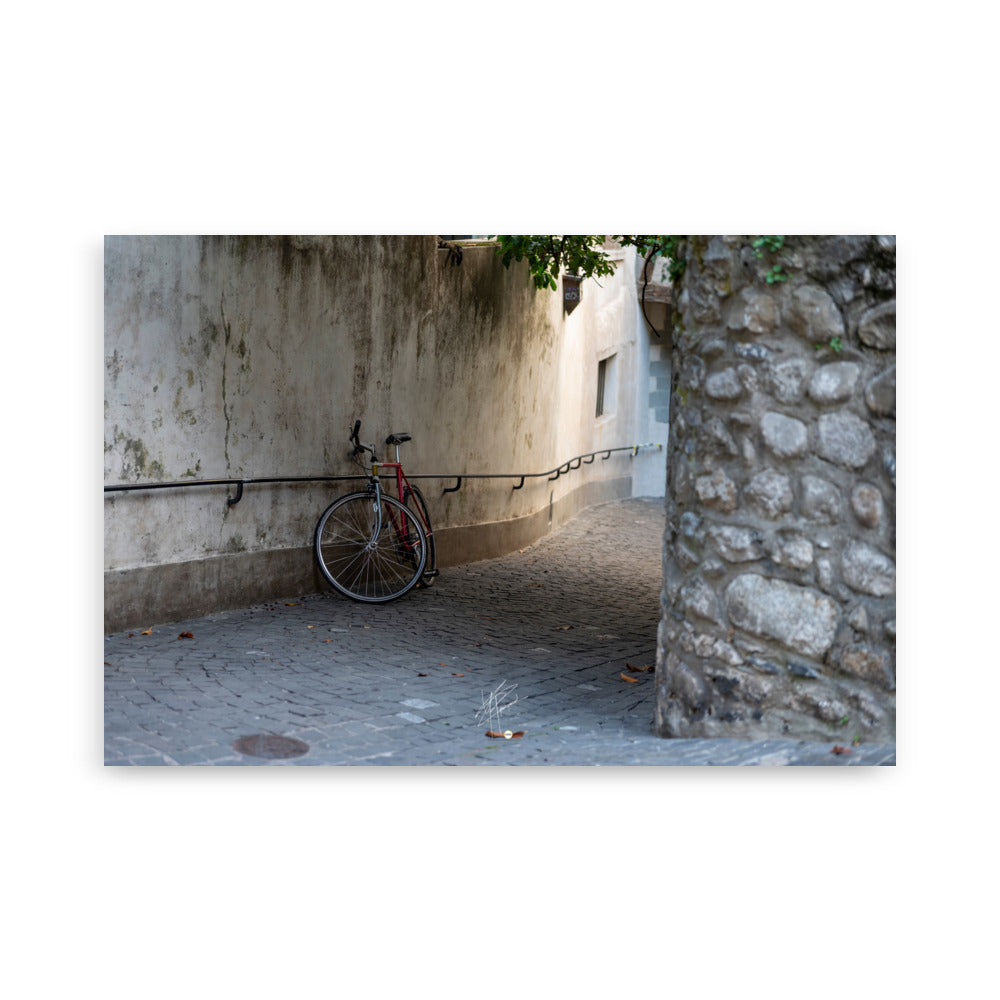 Photographie d'une rue pavée en descente de Genève, sans voitures, avec un vélo non attaché au premier plan. L'atmosphère est paisible et le coucher de soleil ajoute une teinte chaude à la scène.