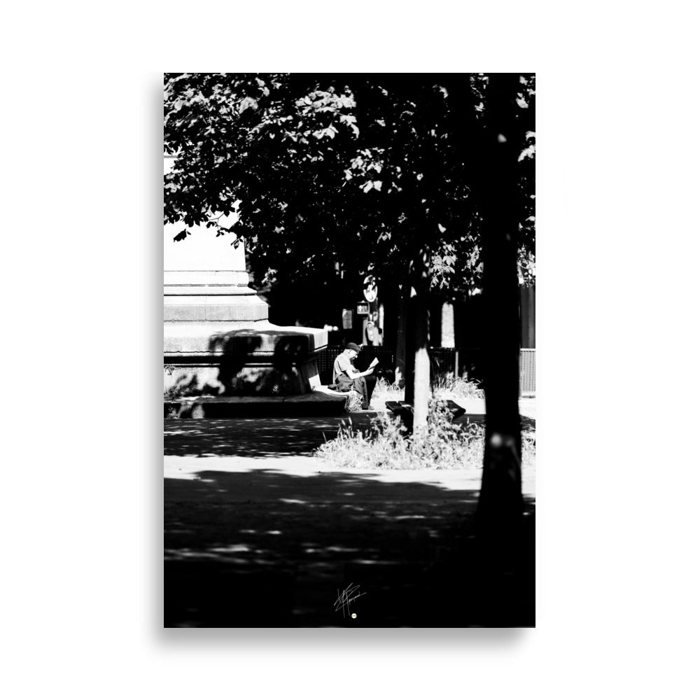 Poster photographique 'L'heure de lire', capturant un homme lisant un livre à Paris, en noir et blanc.