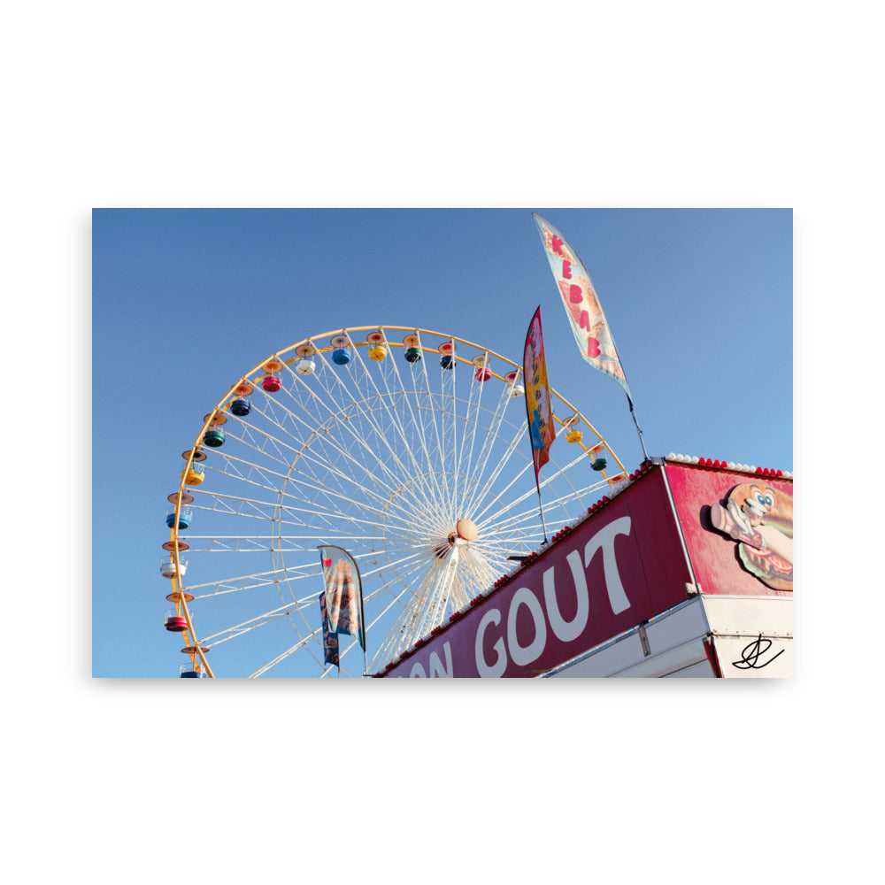 Photographie 'Jour de foire' montrant une grande roue et un kiosque de kebab sous un ciel bleu clair, capturée par Ilan Shoham.