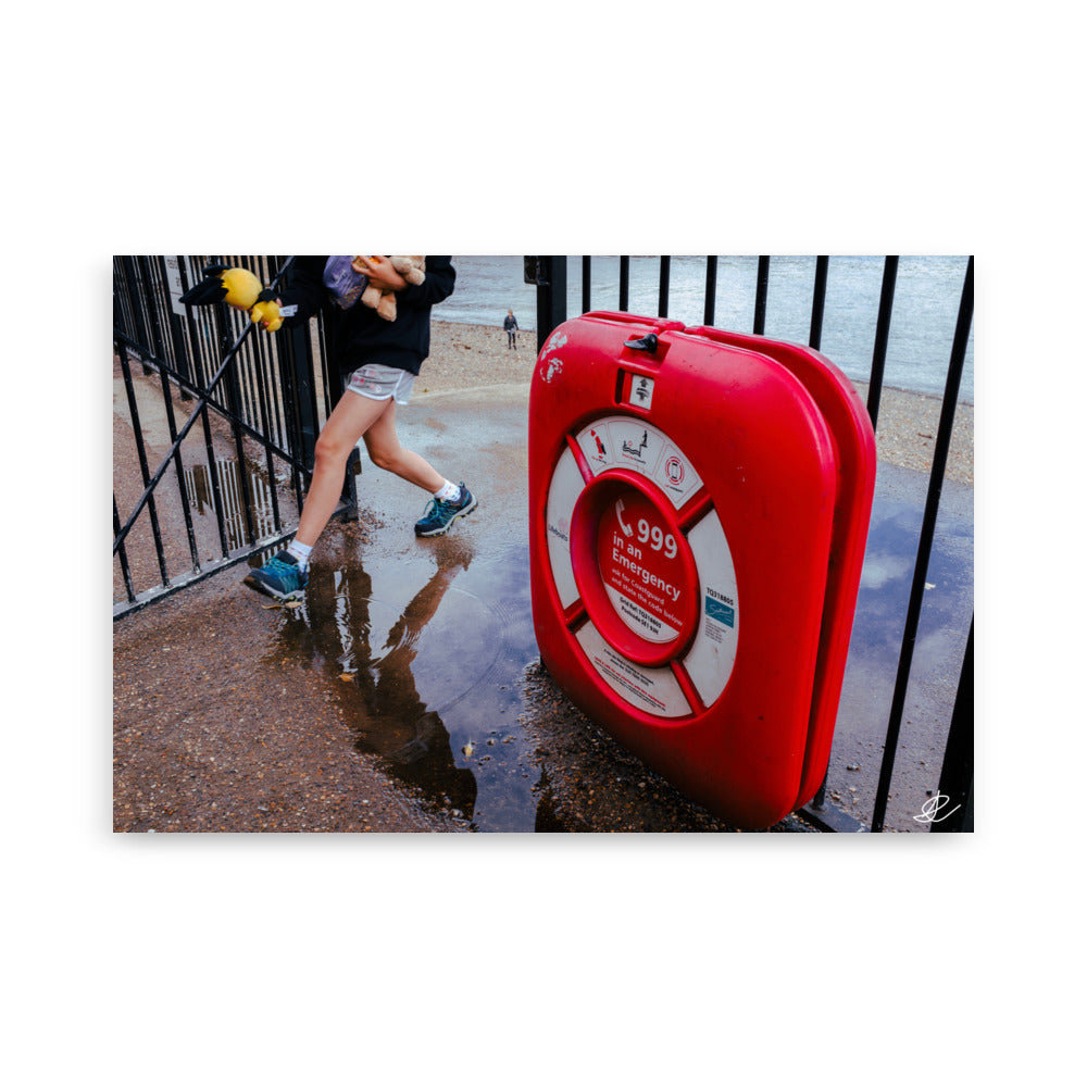 Photographie 'Il faut rentrer' par Ilan Shoham mettant en lumière une boite rouge d'urgence affichant le numéro 999, fixée sur une grille métallique, dans le contexte vibrant des rues de Londres.