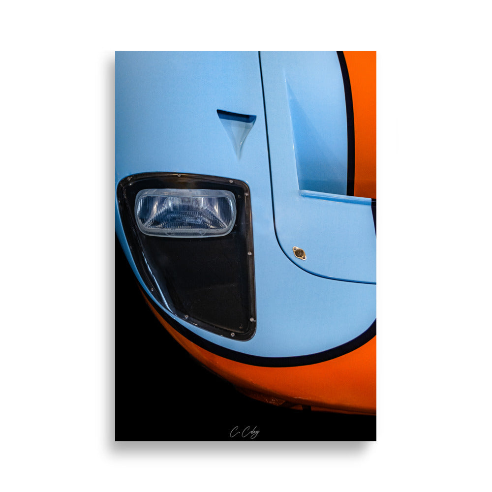 Poster 'GT40 Gulf' capturant la nostalgie de la Ford GT40 à travers un détail du bloc optique vintage et du capot bleu et orange, offrant une plongée visuelle dans l'histoire légendaire des courses automobiles par le photographe Charles Coley.