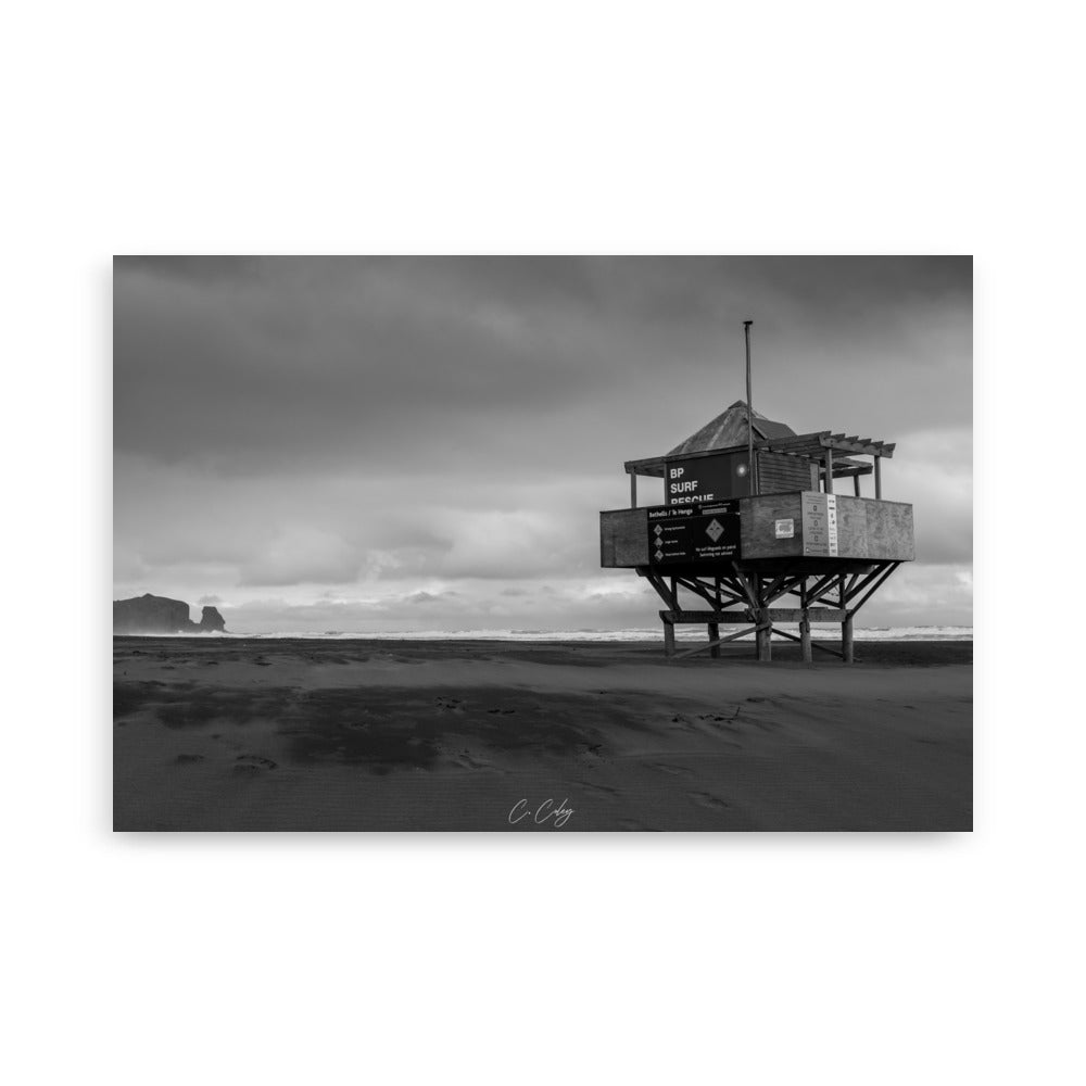 Photographie monochrome de l'emblématique abri sur pilotis des sauveteurs, dominant une plage néo-zélandaise, capturée par Charles Coley.