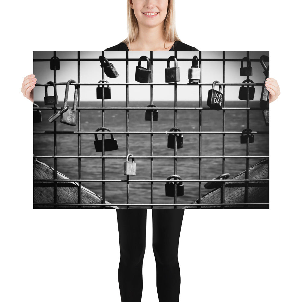 Poster 'L'accroche Cœurs' montrant des cadenas accrochés symbolisant des vœux d'amour avec la mer tranquille en arrière-plan, photographié par Hadrien Geraci. Un choix artistique idéal pour ajouter une touche romantique et d'espoir à votre intérieur.