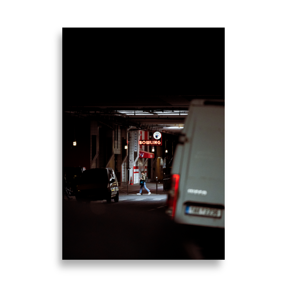 Poster de photographie de rue représentant une passante émergeant de l'ombre sous une enseigne lumineuse de bowling.