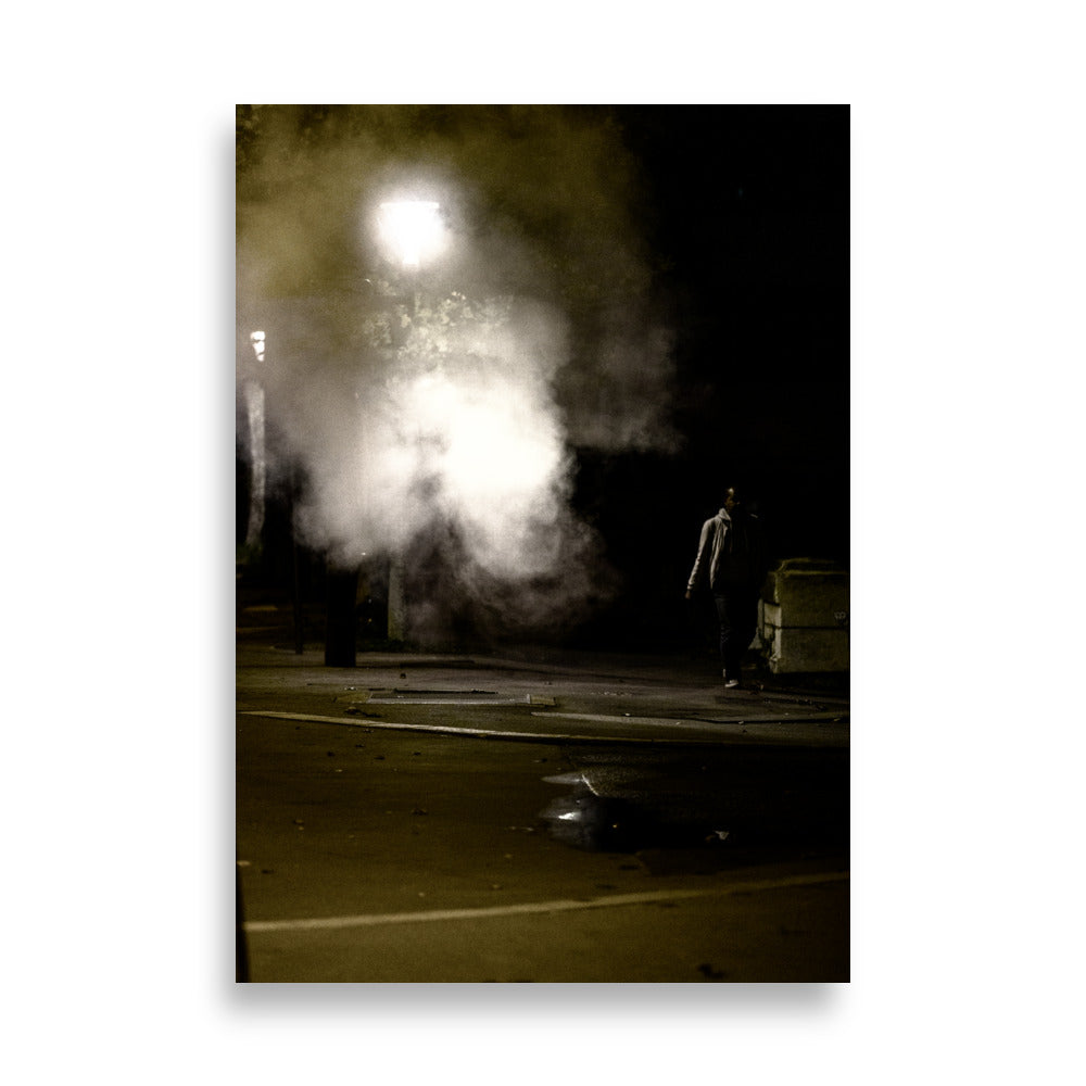 Photographie nocturne de Paris près du Rooftop Café Oz, montrant un homme passant à côté d'une fumée sortant d'une plaque sur le trottoir.