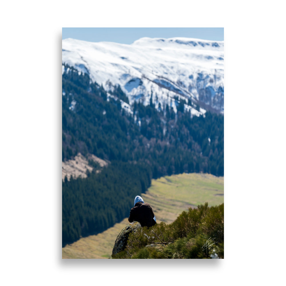 Figure en méditation sur une montagne du Cantal, vaste paysage en arrière-plan.