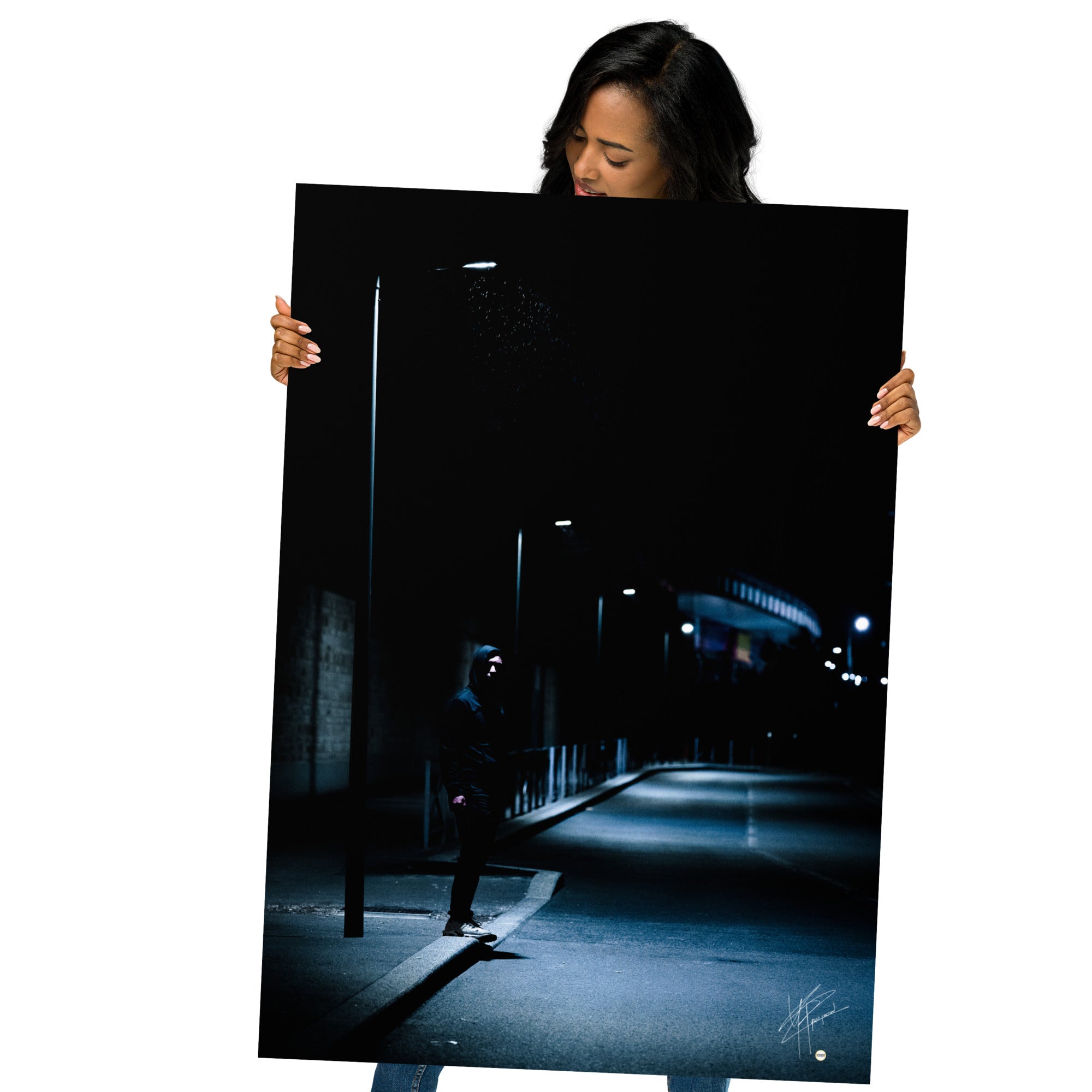 Photographie nocturne d'un homme à capuche se tenant sous un lampadaire près d'une station de métro à Créteil, émanant une atmosphère sombre et énigmatique.