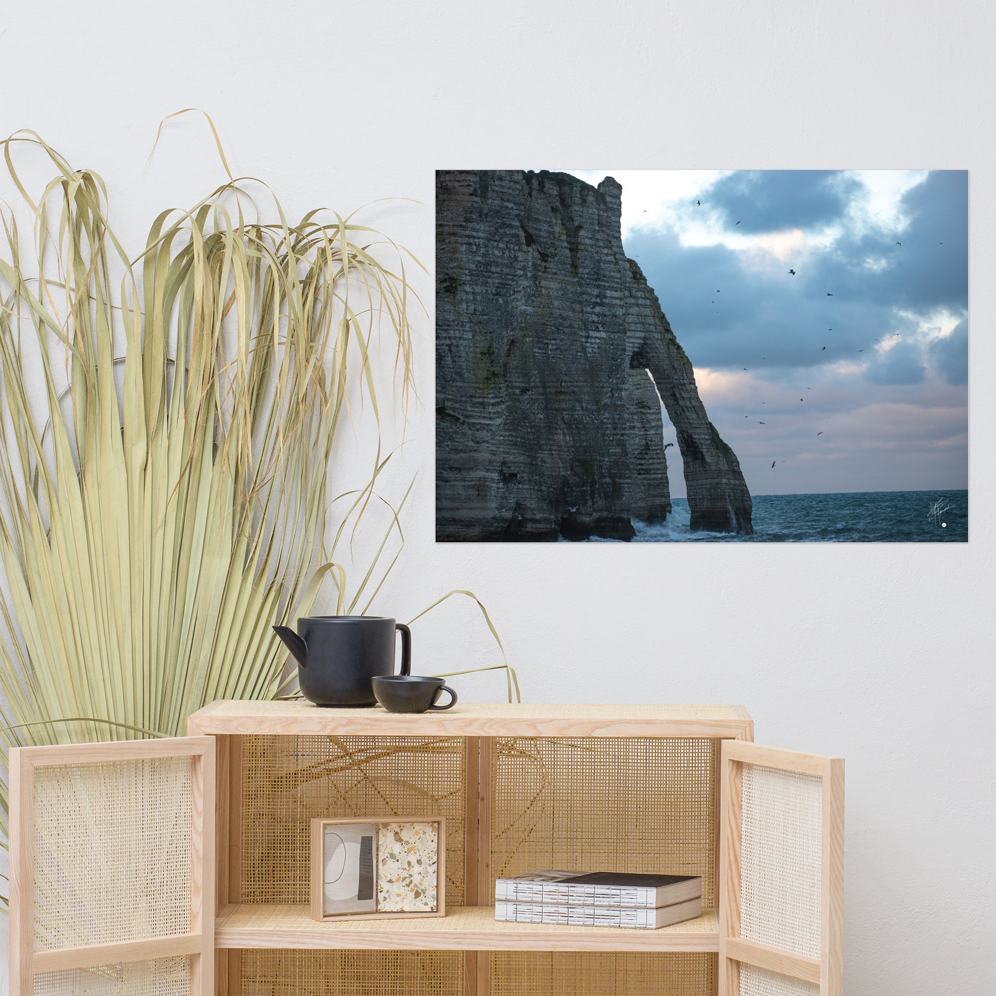 Vue panoramique des falaises d'Étretat avec des vagues s'écrasant puissamment sur la côte, sous un ciel nuageux où les mouettes virevoltent, incarnant la beauté sauvage de la Normandie.