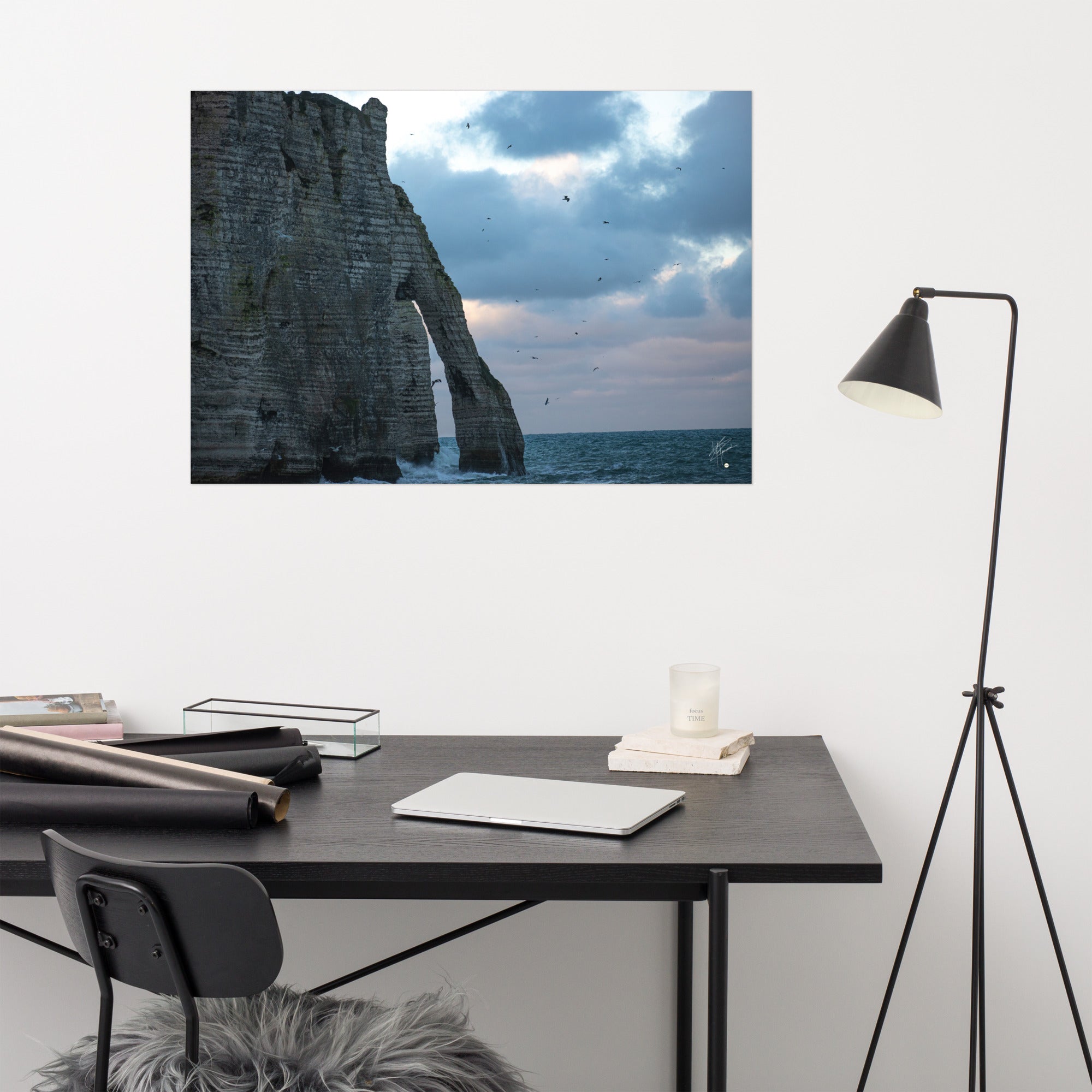 Vue panoramique des falaises d'Étretat avec des vagues s'écrasant puissamment sur la côte, sous un ciel nuageux où les mouettes virevoltent, incarnant la beauté sauvage de la Normandie.