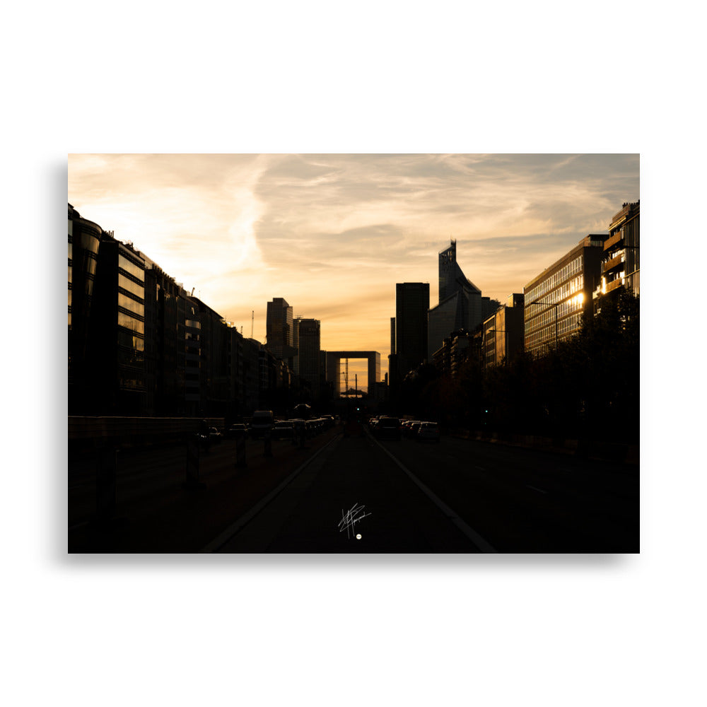 Coucher de soleil orangé illuminant le paysage urbain moderne de La Défense avec ses tours imposantes et ses structures en verre.