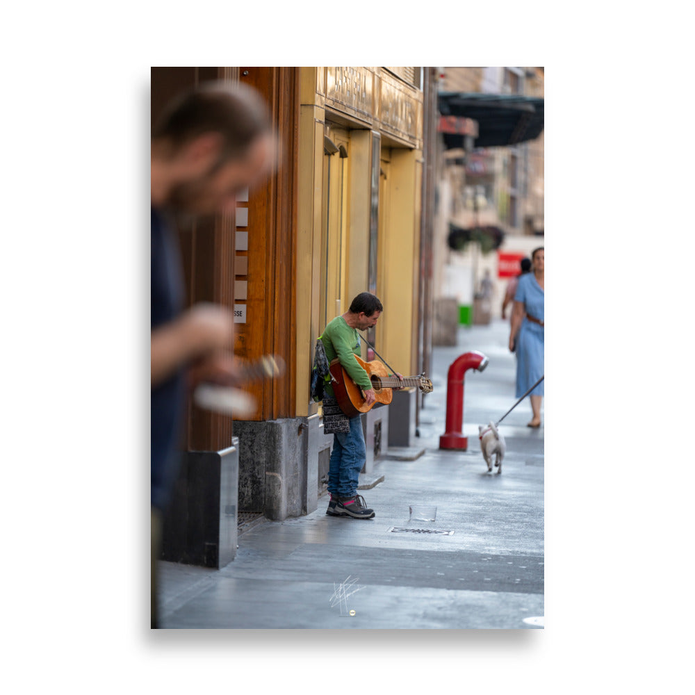 Poster photographique 'Le Petit Guitariste', une image d'un homme jouant de la guitare acoustique dans les rues de Genève, symbolisant la passion et la créativité de la musique de rue.