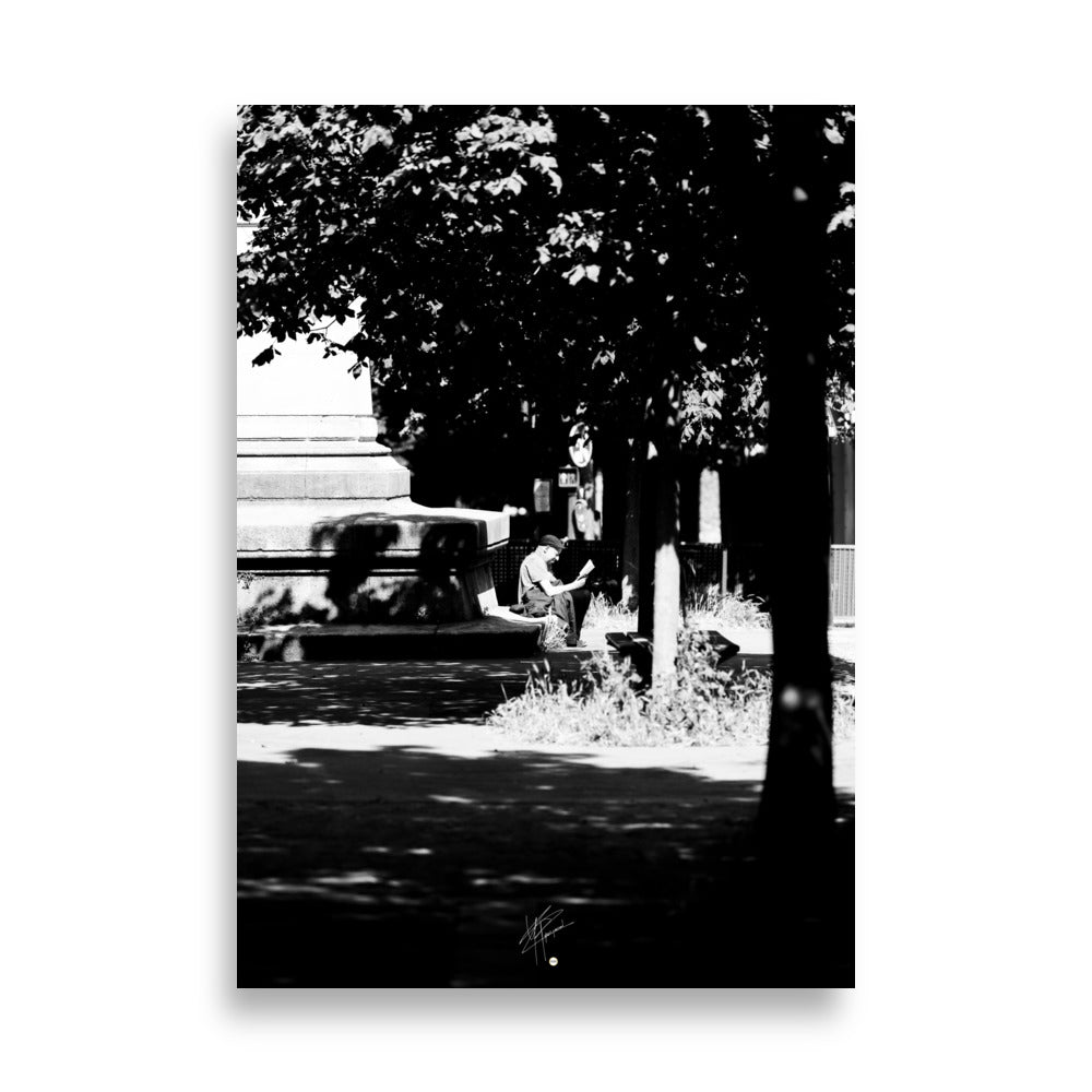 Poster photographique 'L'heure de lire', capturant un homme lisant un livre à Paris, en noir et blanc.