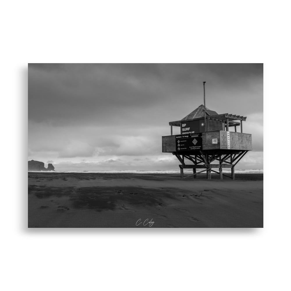 Photographie monochrome de l'emblématique abri sur pilotis des sauveteurs, dominant une plage néo-zélandaise, capturée par Charles Coley.