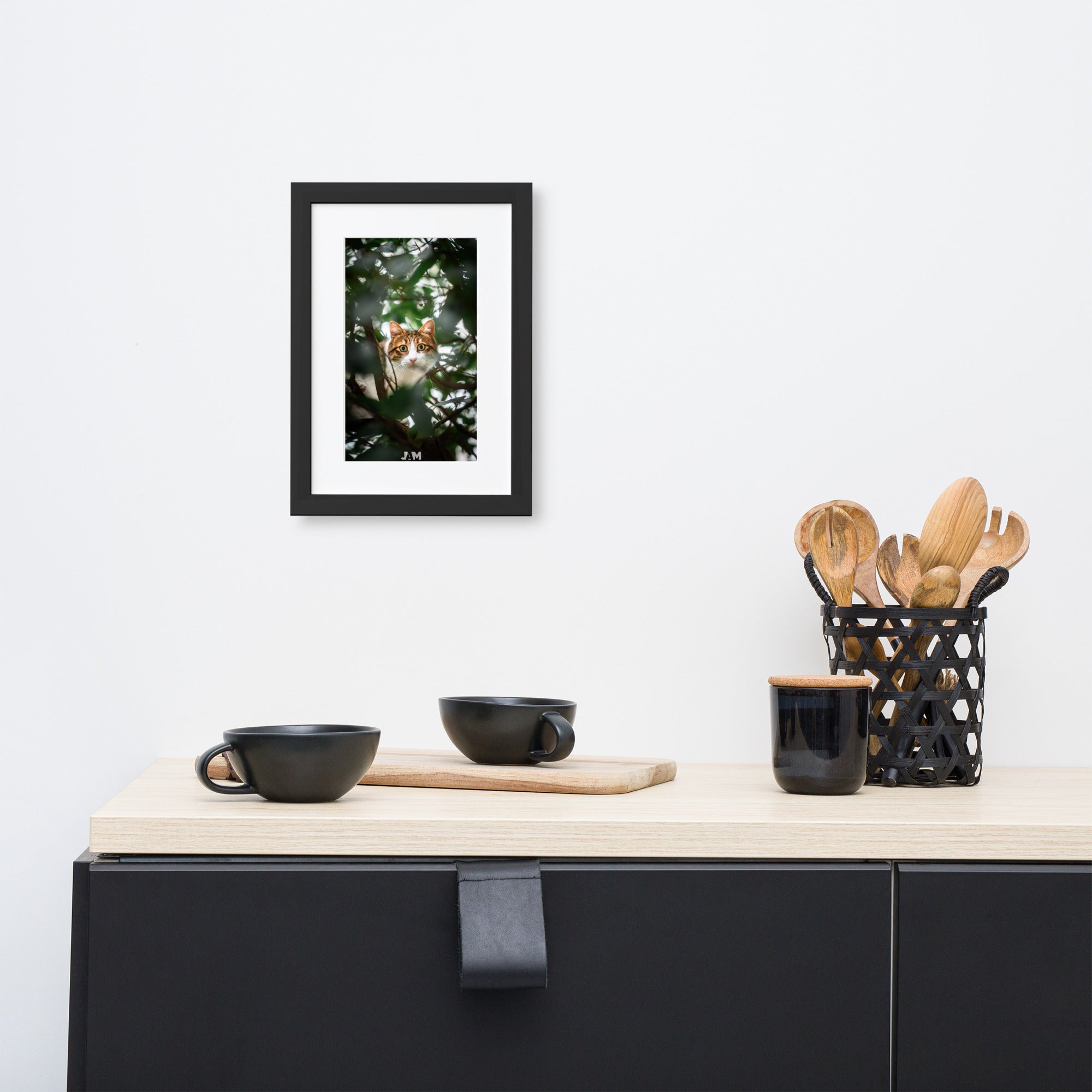 Poster 'Gros yeux', mettant en scène un chat dissimulé derrière des plantes, ses yeux largement ouverts fixant l'objectif avec intense curiosité et malice, capturé magnifiquement par le photographe Julien Arnold.