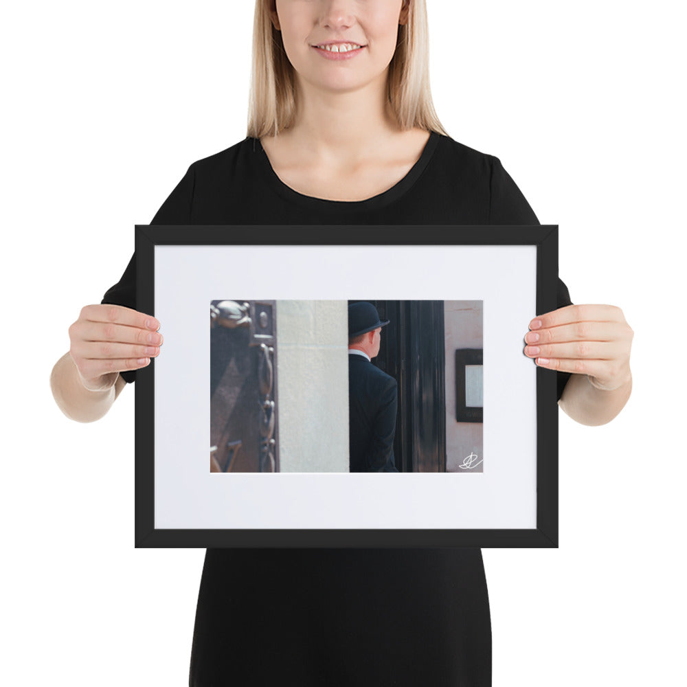 Photographie en noir et blanc 'Gardien d'Entrée' par Ilan Shoham, montrant un homme en costume noir vue de dos, patientant à l'entrée d'un édifice à Londres.